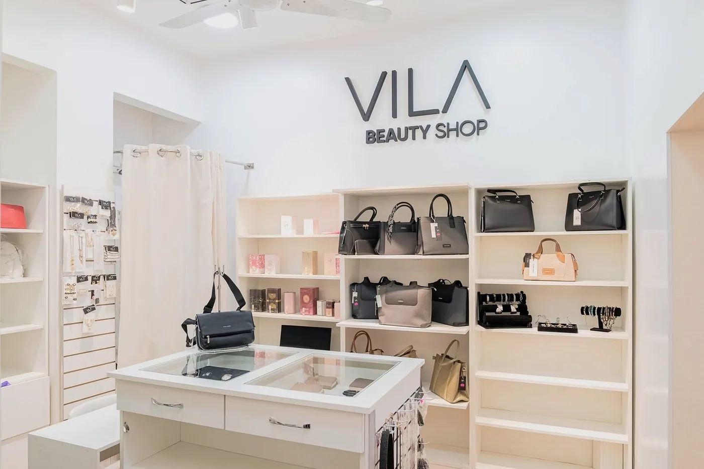 Interior de Vila Beauty Shop con carteras, perfumes y accesorios bajo el logo de la tienda