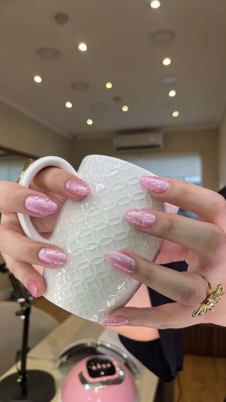 Uñas con glitter rosa sosteniendo una taza en el salón